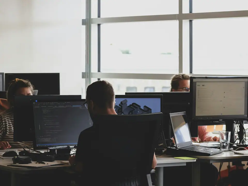Equipo de desarrollo trabajando frente a monitores con código de software